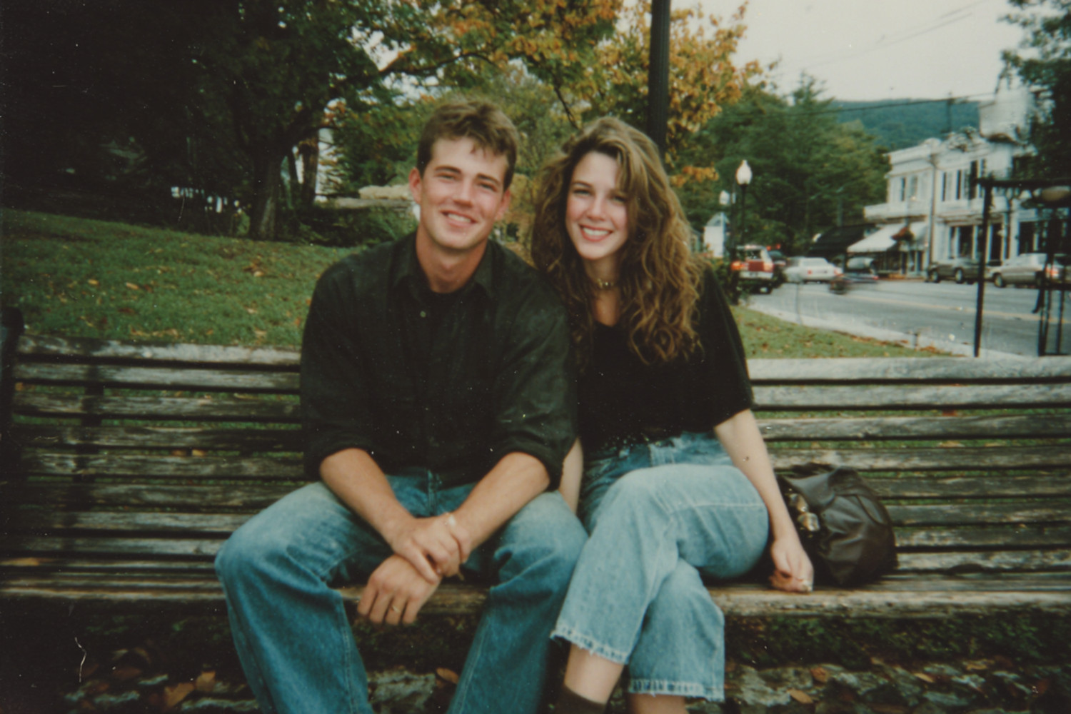Ein Mann und eine Frau sitzen lächelnd auf einer Bank. Das Bild wirkt etwas unscharf und als ob es in den 90ern aufgenommen worden wäre.