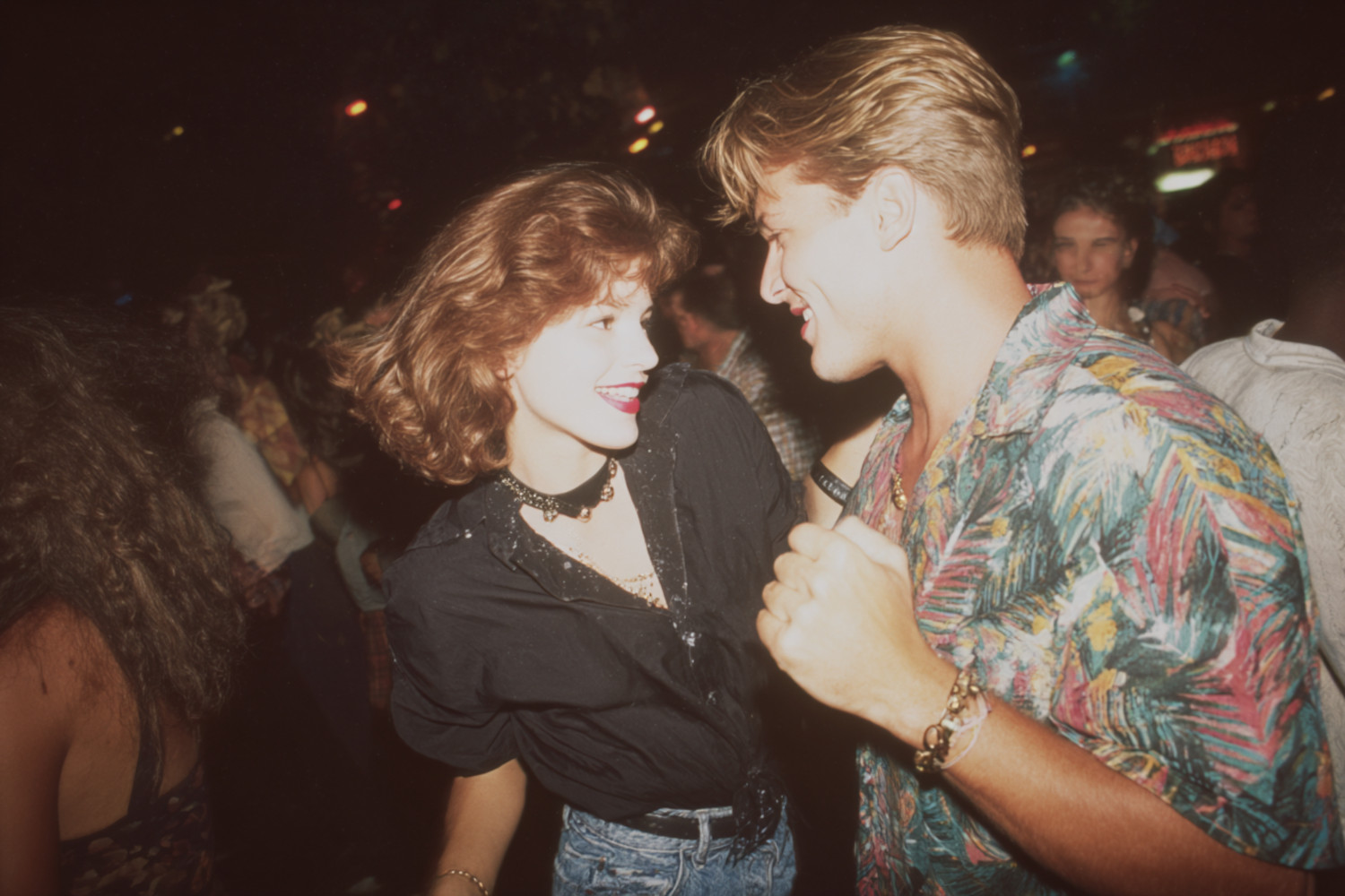 Ein Mann und eine Frau tanzen in einem Club, sie tragen Kleidung im 90ies-Style