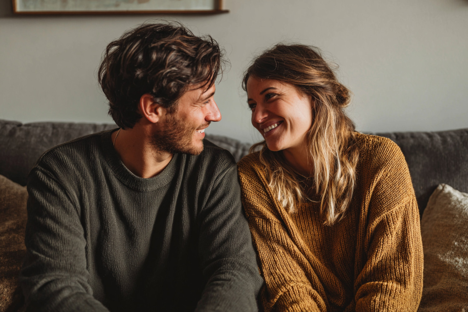Ein Mann und eine Frau sitzen nahe beieinander auf einem Sofa und lächeln sich an