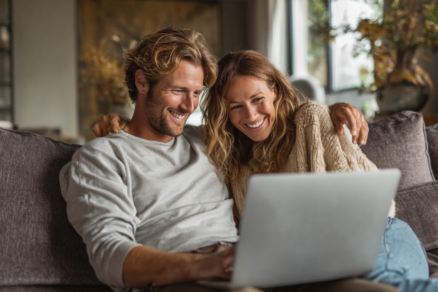 Ein Paar sitzt auf dem Sofa und schaut gemeinsam auf einen Laptop