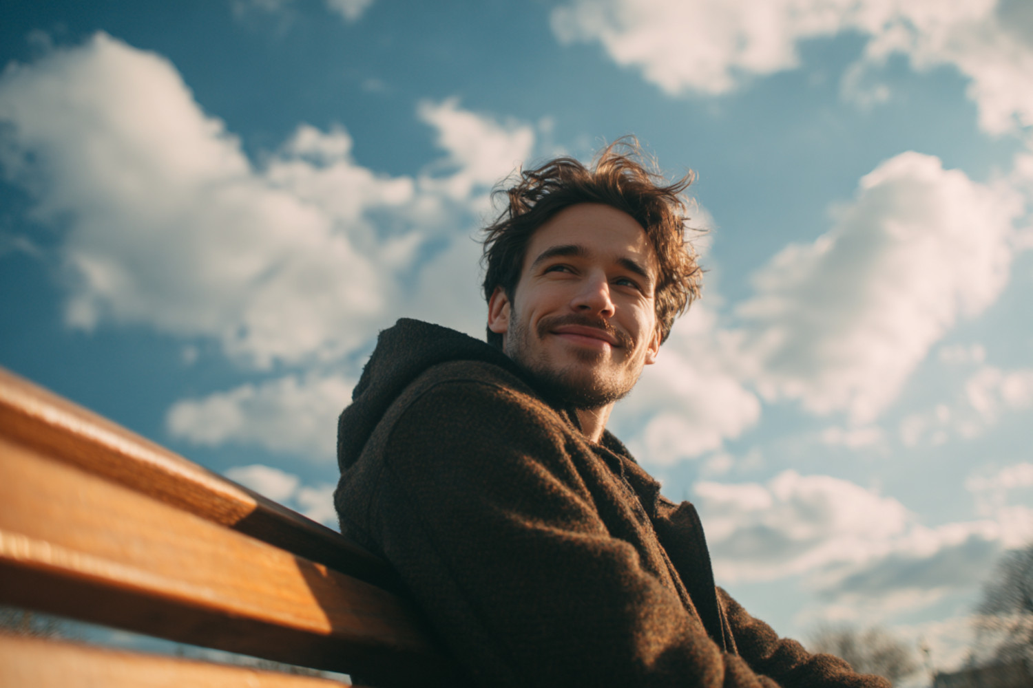 Ein Mann sitzt versonnen lächelnd auf einer Bank
