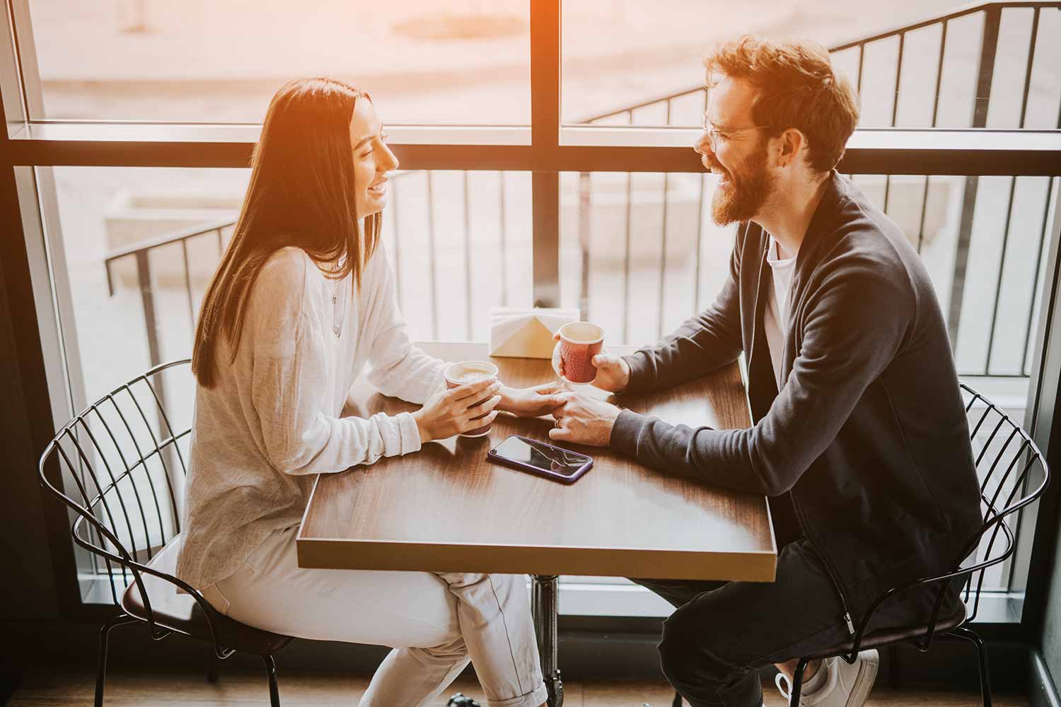 Fröhliches junges Paar mit Kaffee beim ersten Date