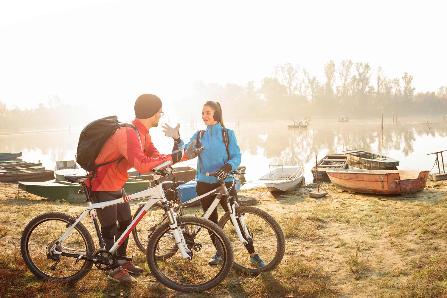 Junges Paar mit Mountainbikes am See bei Sonnenschein und Nebel