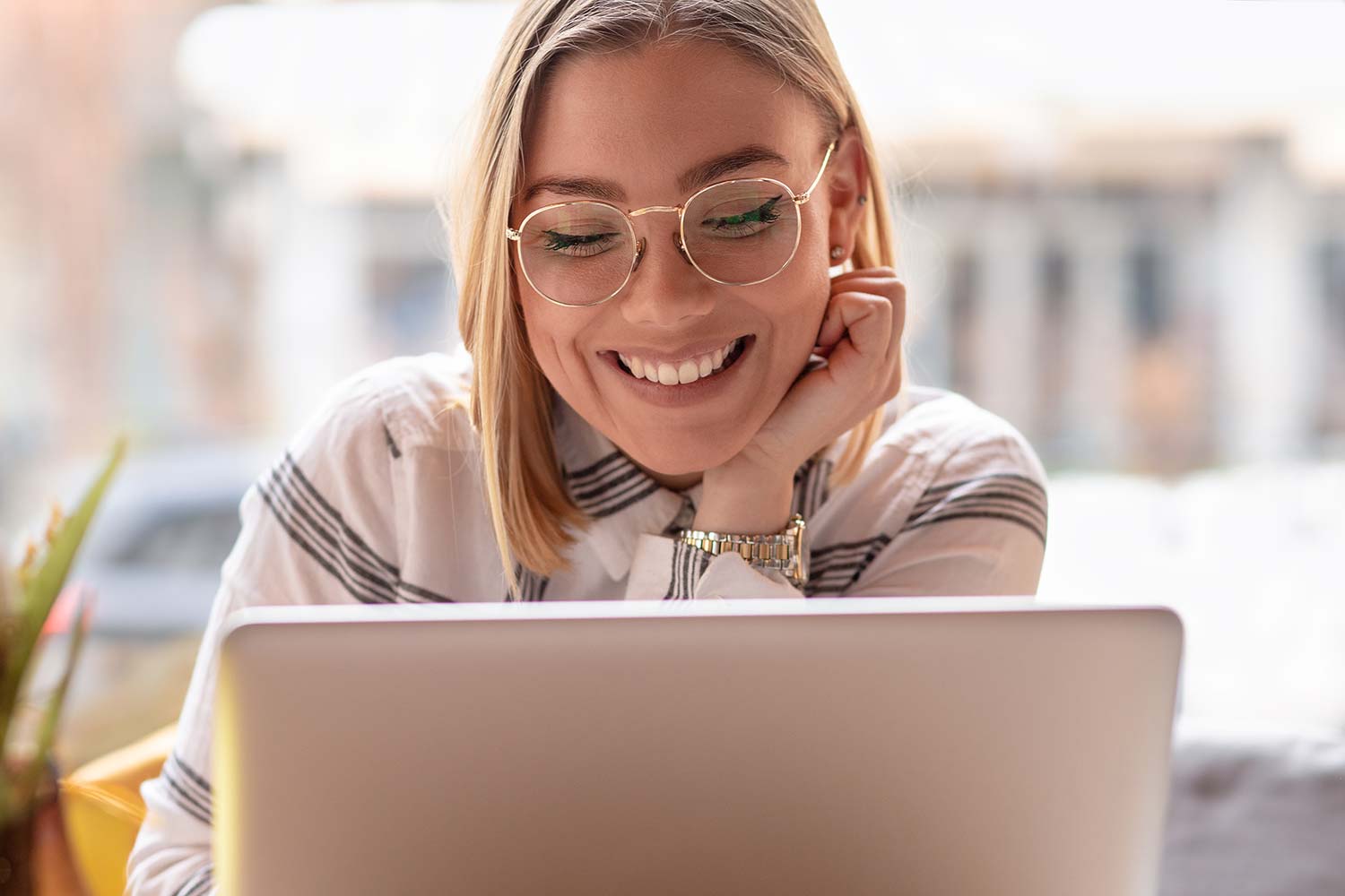 Junge lächelnde Frau mit Laptop im Café
